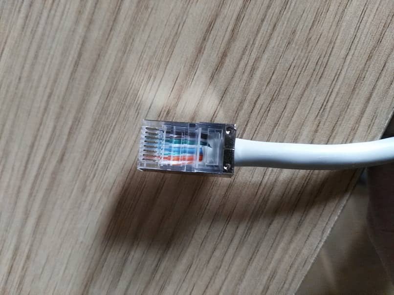 Una foto ampliada de un cable ethernet blanco con los ocho colores de cableado interno 